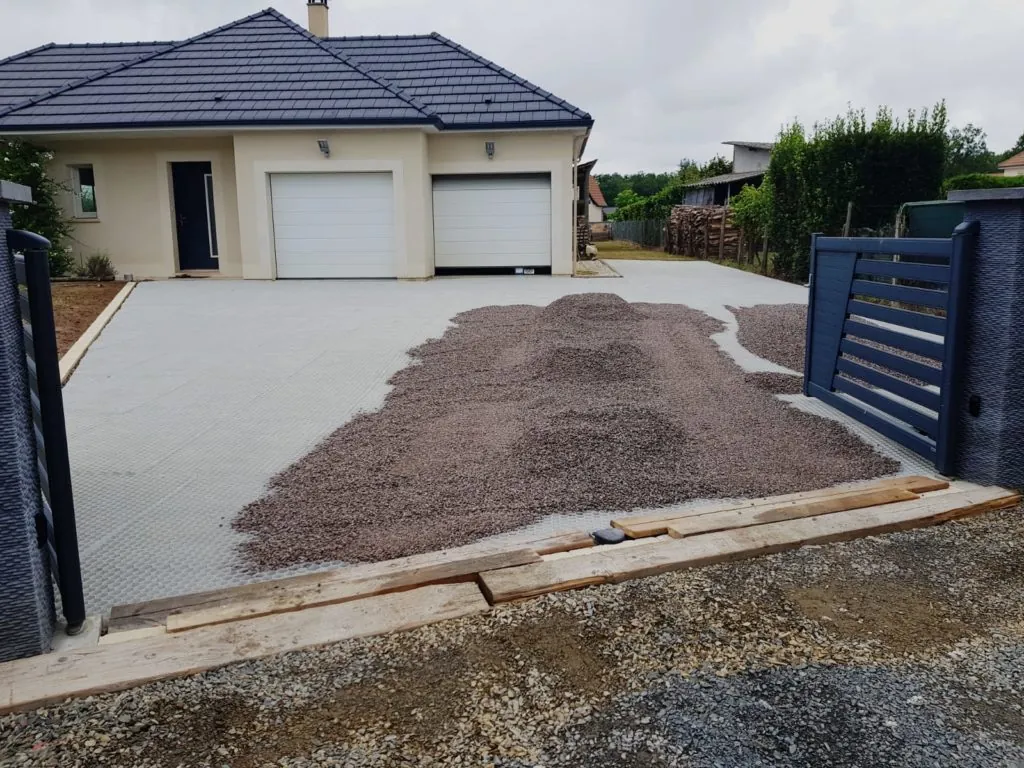 Préparation de l'allée d'une propriété avec pose de stabilisateurs de gravier alvéolés et tas de gravillons.